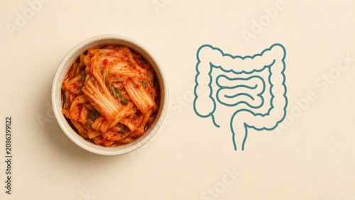 Fermented kimchi bowl beside teal gut outline icon on beige background, flat lay top view, minimal health concept, clean cream surface
