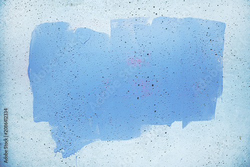 Φωτογραφία A rectangular swath of blue paint on a rough concrete wall, showing drips, speck