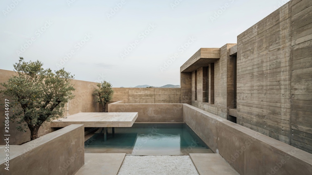 Fototapeta premium Swimming pool sits adjacent to a raw concrete structure with minimalist design elements and desert landscaping.