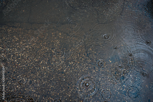 Принти на полотні Close-up of rainwater on dark asphalt with round ripples of raindrops, gravel texture and reflective wet surface