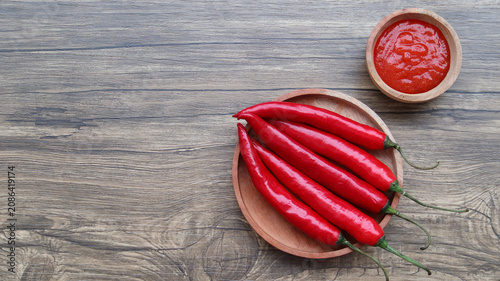 Billede på lærred Chilli sauce and fresh peppers on wooden background