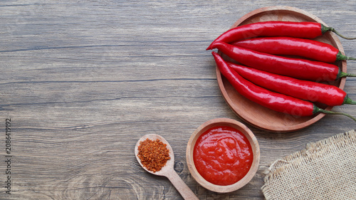 Cuadro en lienzo Chilli sauce, chilli flakes and fresh peppers on wooden background