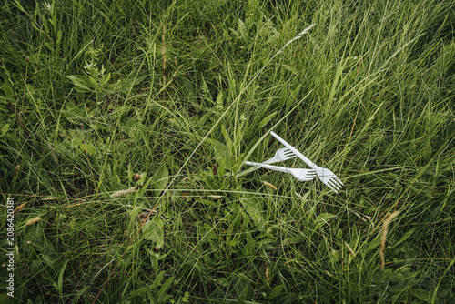Картината върху платно A used syringe lying in long, green grass illustrates the pollution of medical waste, public health risks, and improper disposal in the natural environment