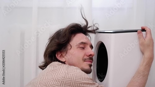 Happy man cooling down in front of an air cooler fan during a summer heatwave at home