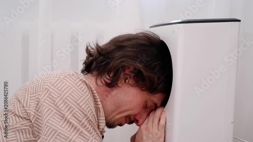 Young man cooling his head with a bladeless fan during a hot summer day at home