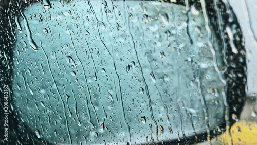 Canvas Print Heavy rain streaks flowing down car window with blurred vehicle outside