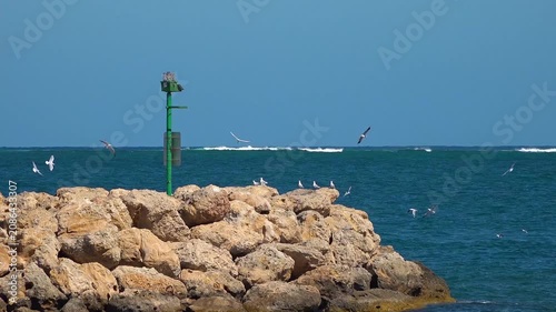 Rocky sea coast of Crete with blue ocean waves, stone cliffs and sandy beach under summer sky, scenic Mediterranean coastline landscape