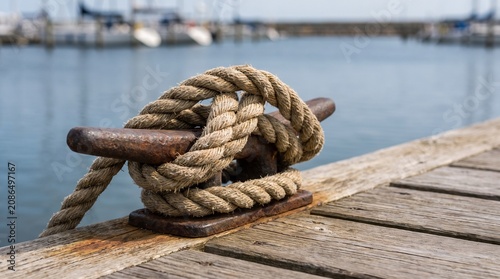 Taut mooring line secured to dock cleat by water in harbor  