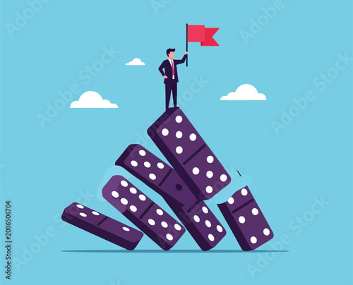 Business success concept with businessman standing on top of falling domino stack holding red flag symbol of achieving goals through adversity and crisis.