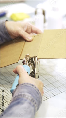 Woman's hands using a hole puncher for scrapbooking