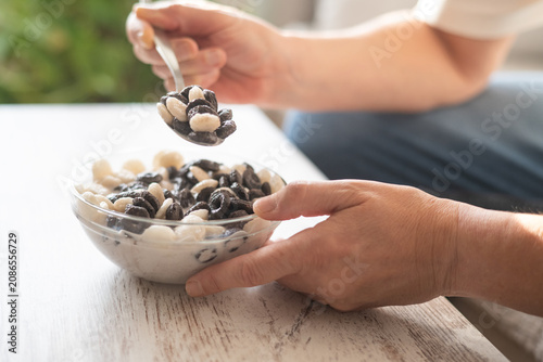 Fotografía Person holding a bowl of black and white cereal with milk and scooping a spoonfu