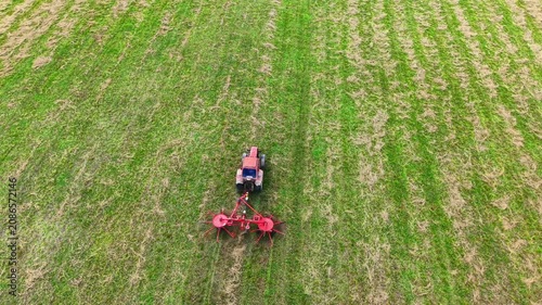 Tractor tilling fertile green field with patterned rows of freshly cut grass and soil
