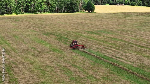Spreading fresh cut hay in open fields creates lush green textures under bright sunlight, aerial view