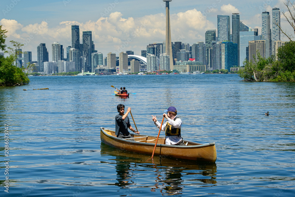 Obraz premium Canoe paddlers below Toronto city skyline