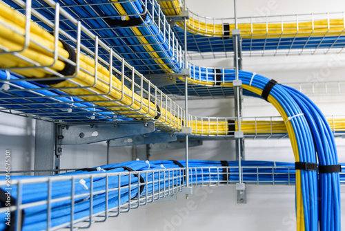Organized network cables in blue and yellow neatly routed through wire mesh trays