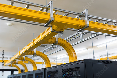 Modern data center with bright yellow cable management systems above server racks