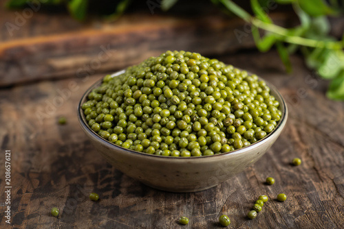 Heap of raw mung beans or moong dal on rustic wooden table.
