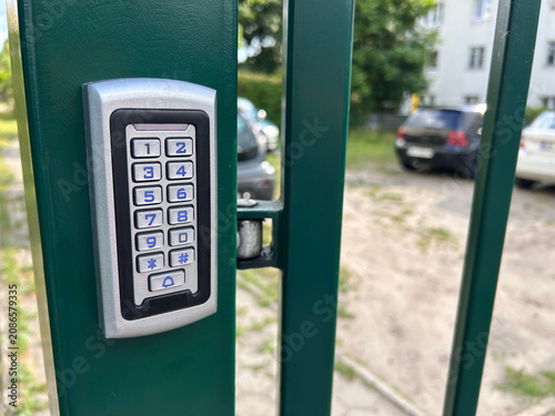 Electronic keypad access control mounted on a green metal gate for secure property entry