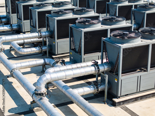 Obraz na plátně Industrial HVAC units with large metal pipes on a rooftop under bright sunlight