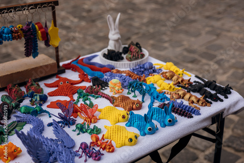 Colorful articulated 3D printed figurines displayed at an outdoor street market.