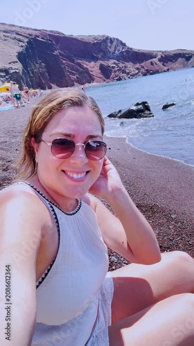 Female vlogger taking a selfie at red beach in santorini, greece