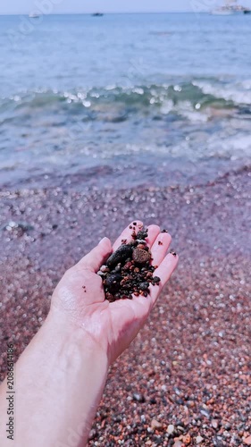 Person holding red volcanic sand at red beach in santorini, greece