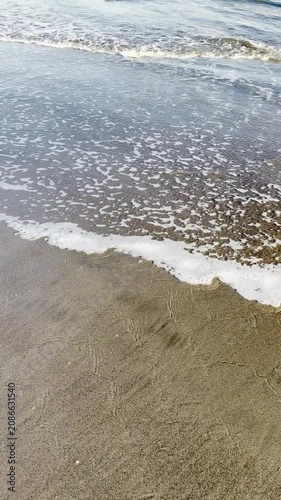 Gentle Ocean Waves Receding Over Wet Sand on a Peaceful Summer Beach Shore