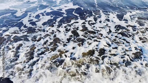 Crashing Ocean Waves Flowing Over Dark Pebbles on a Scenic Coastal Shoreline