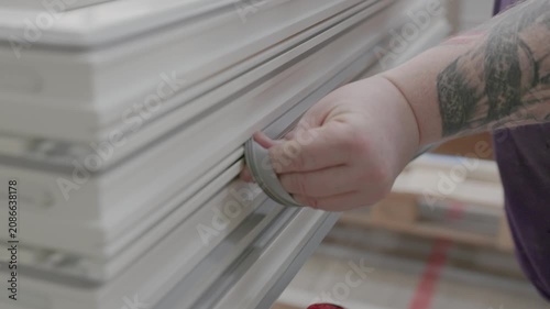 Close-up of a worker fitting rubber insulation gasket into stacked window frames during workshop assembly