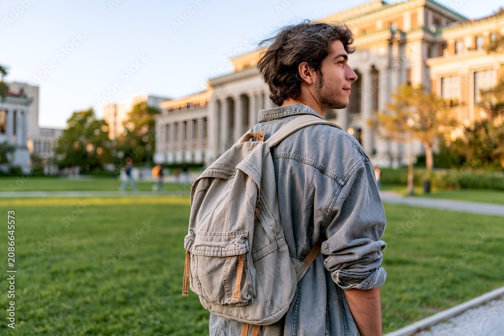 Fototapeta premium Young man stands on campus lawn.