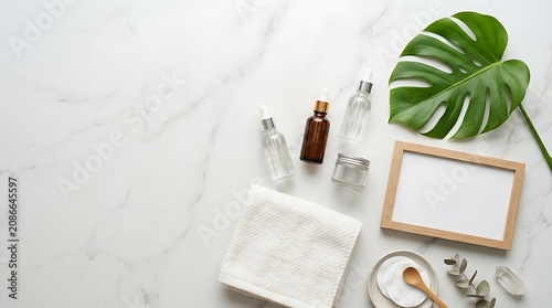 Overhead flat lay of luxury skincare routine products with empty blank mirror frame mockup