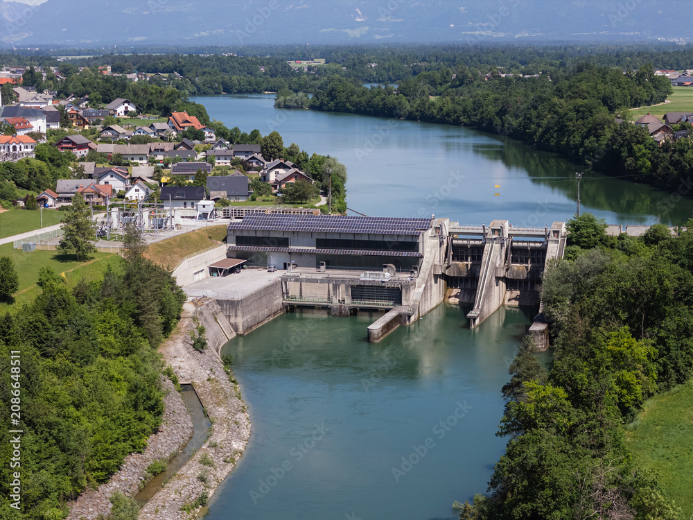 Obraz premium Hydropower plant generates clean electricity from river water. Infrastructure supports green energy production and sustainability goals.