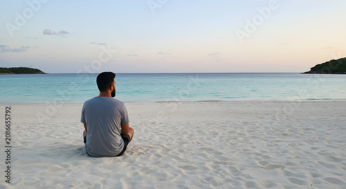 Man Sitting on Empty Beach at Sunset Reflecting on Life and Enjoying the Peaceful Ocean View in Tropical Paradise