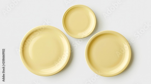 Soft yellow plates arranged in a top view layout on a light background, showcasing three different sizes for versatile dining and serving options