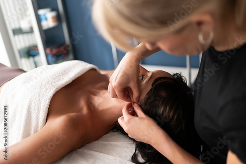 Foto Female patient receiving therapeutic neck and shoulder massage in bright treatme