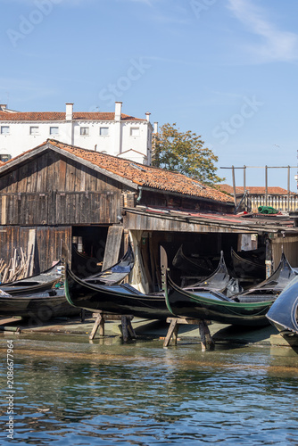 Gondolas in repair at a workshop in Venice during a sunny day by the water