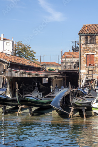 Gondolas in repair at a workshop in Venice during a sunny day by the water