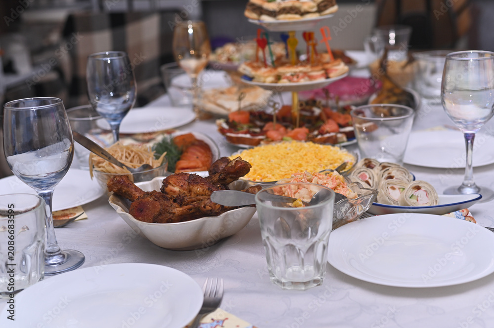 Fototapeta premium Assorted party food served on white tablecloth during holiday dinner. Many delicious dishes like meat snacks and fresh salads are ready for guests. Gourmet catering service for big banquet.