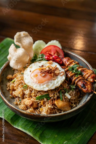 Indonesian Nasi Goreng Fried Rice with Fried Egg Chicken Satay and Prawn Crackers in Ceramic Bowl