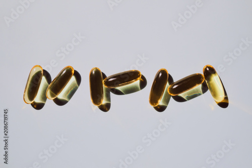Schilderij op canvas Yellow softgel capsules casting shadows on light background