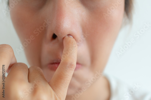 Photos Close-up of a young Thai woman pinching her nose, showing disgust from a bad smell