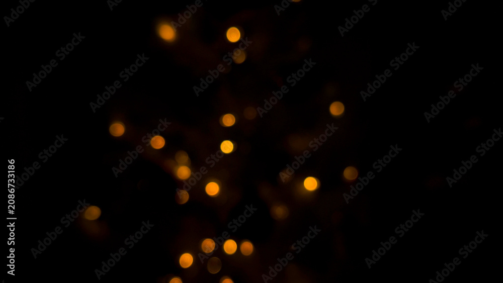 Fototapeta premium Light bokeh forming warm golden glowing dots on deep black background with soft blur. Light creating dreamy abstract illumination pattern, festive sparkle mood, night decoration concept, texture
