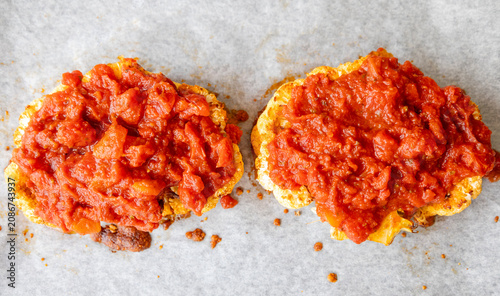 Close-up of golden roasted cauliflower steaks baked in a sheet pan, smothered with rich herb tomato sauce