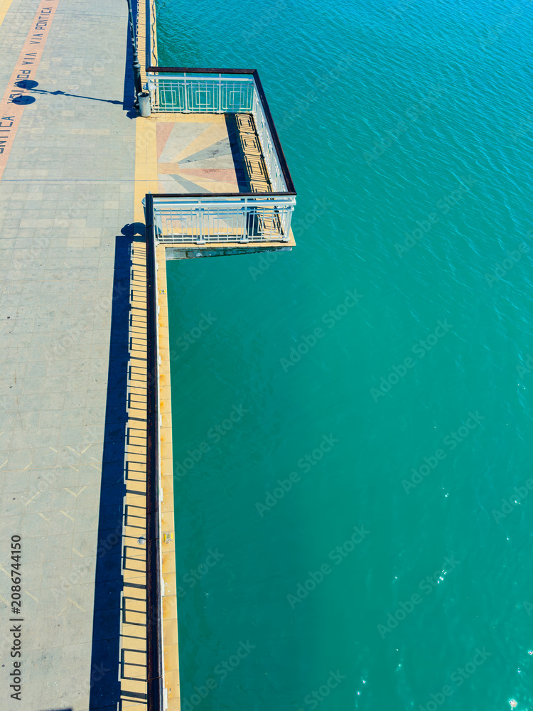 Fototapeta premium Building structure extends over water in a coastal area with bright colors during daylight hours showing clear blue water
