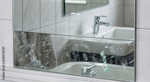 Dirty bathroom mirror with smudges and fingerprints showing need for cleaning.