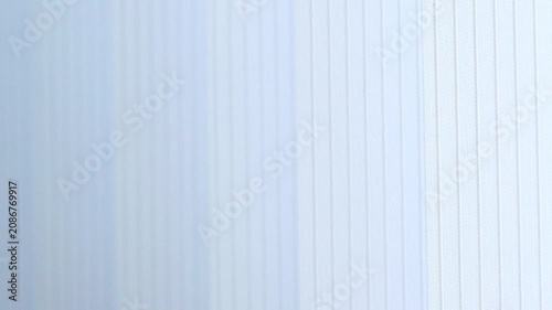 Abstract view of moving white window blinds in soft breeze.