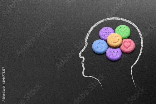 Human head silhouette filled with MDMA or Ecstasy pills on black background