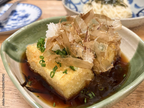 Crispy agedashi tofu topped with grated radish and bonito flakes in savory soy broth, warm comforting Japanese appetizer