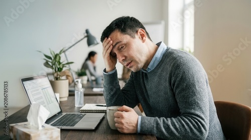 Man Feeling Exhausted And Stressed At His Desk While Working