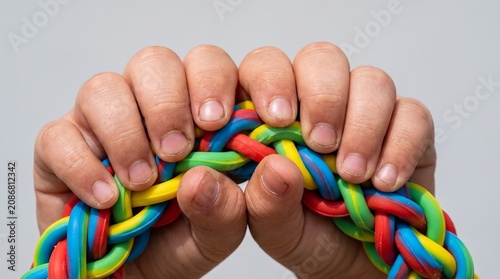 Close-up of hands holding a colorful braided rubber rope with bright rainbow colors